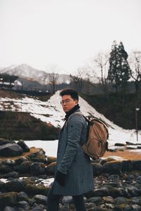 Man standing on rock against sky during winter