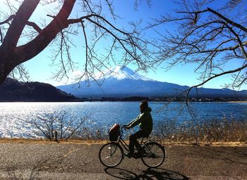 Man with bicycle on lake against sky