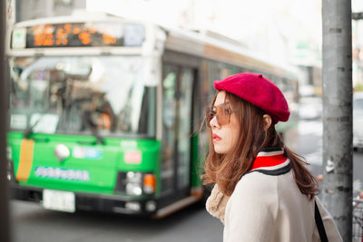 Side view of woman looking away while standing on street