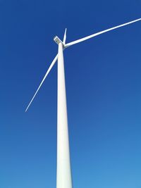 Low angle view of wind turbine against blue sky