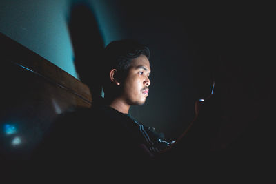 Side view of young man looking at camera