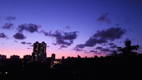 Silhouette buildings against sky at sunset