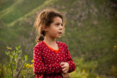 Cute girl scratching hand while standing on field