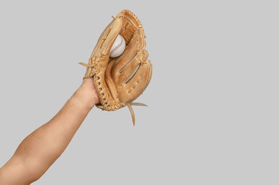 Cropped hand of person wearing hat against white background