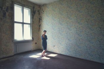 Full length of woman standing against wall at home