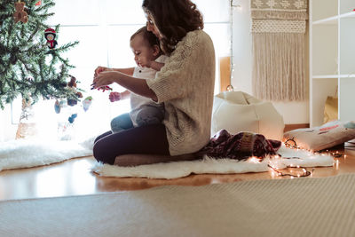 Women sitting on christmas tree at home