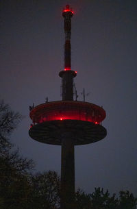 Low angle view of illuminated tower against sky at dusk