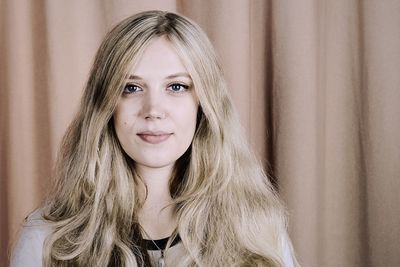 Portrait of smiling young woman against curtain