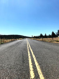 Empty road against clear blue sky