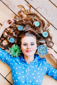 Portrait of a smiling young woman lying on wooden floor