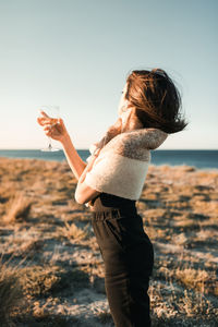 Side view of woman standing on land against sky