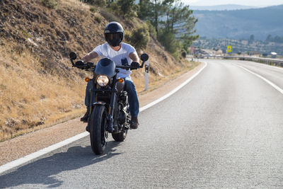 Rear view of man riding motorcycle on road