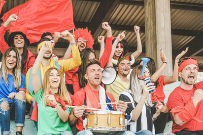Excited people sitting with musical instruments in stadium