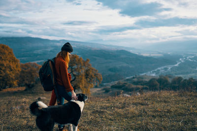 Man with dog on mountain against sky