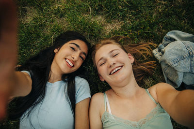 Portrait of happy teenage girls lying on grass at park