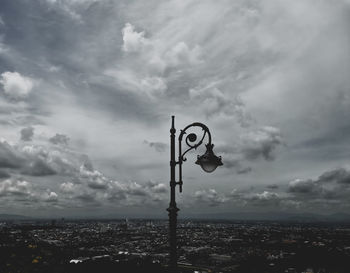 Information sign by pole against sky in city