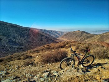 Bicycle parked on desert against clear blue sky