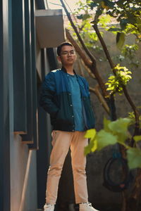 Portrait of young man standing against plants