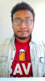 Portrait of young man wearing eyeglasses against wall