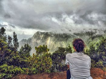 Silhouette of man standing on mountain against cloudy sky