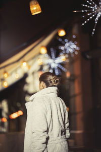 Woman wearing warm clothing while standing in city at night