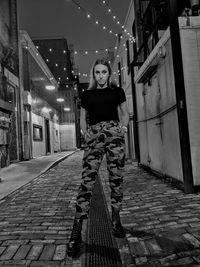 Portrait of young woman standing against built structure at night