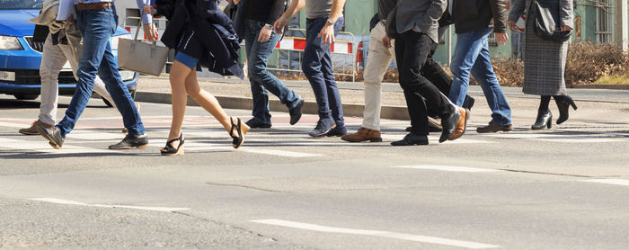 A crowd of pedestrians crossing street in the city, low section of people walking on city street.