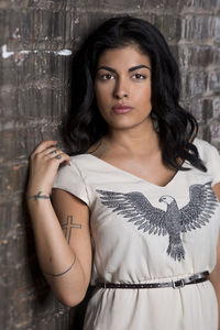 Portrait of beautiful young woman standing against wall