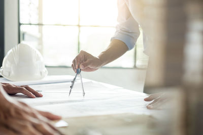 Midsection of architect working on blueprints