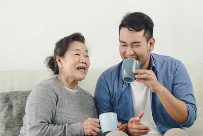 Happy mother and son having coffee at home