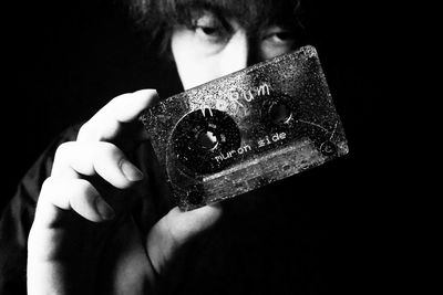 Close-up portrait of boy holding leaf against black background