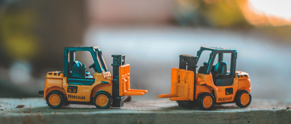 Close-up of yellow toy forklifts on wood