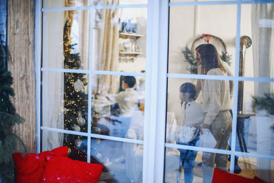 Rear view of woman standing by window