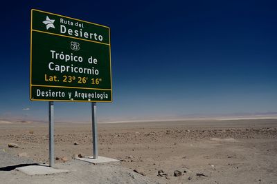 Information sign on sand at beach against sky