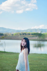 Portrait of young woman standing against lake