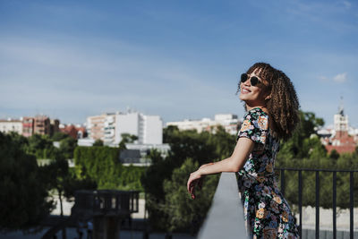 Young woman standing against sky in city