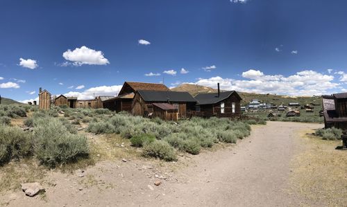 Houses on field by buildings against sky