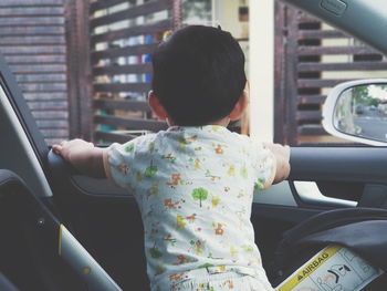 Rear view of boy sitting in car