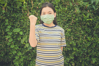 Portrait of young woman standing against plants