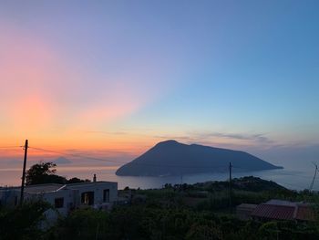 Scenic view of sea and buildings against sky during sunset