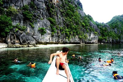 People swimming in sea against rock formation