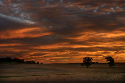 Scenic view of dramatic sky over land during sunset