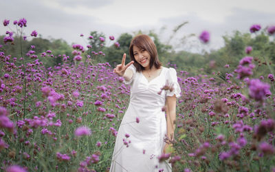 Portrait of young woman standing amidst flowers