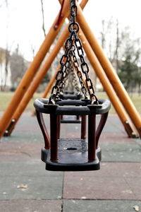 Close-up of empty swing in park against sky