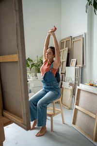 Full length of young woman exercising on chair at home