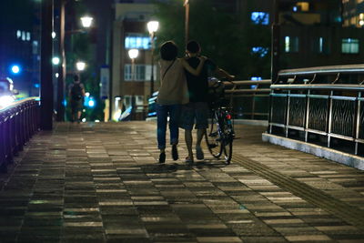 Rear view of people riding bicycle at night