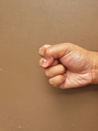 Close-up of human hand. clenched fist, brown background