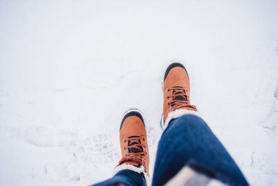 Unrecognizable female feet boots walking on snowy landscape during winter. hiking concept, top view