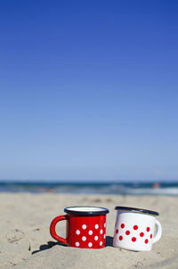 Close-up of red wine on beach against clear blue sky