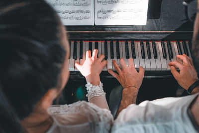 Rear view of people playing piano